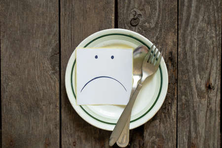 sad udibka drawn on a piece of paper lies on an empty plate on the table, sadness when there is nothing to eat, hunger and bad moodの写真素材