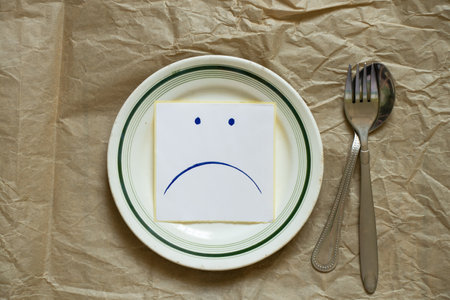 sad udibka drawn on a piece of paper lies on an empty plate on the table, sadness when there is nothing to eat, hunger and bad moodの写真素材