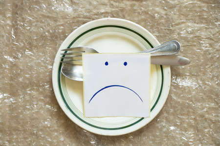 sad udibka drawn on a piece of paper lies on an empty plate on the table, sadness when there is nothing to eat, hunger and bad moodの写真素材