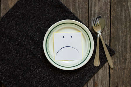 sad udibka drawn on a piece of paper lies on an empty plate on the table, sadness when there is nothing to eat, hunger and bad moodの写真素材
