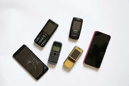 Ukraine Dnipro 08/10/2021 - phones of different models and different generations and brands lie on a white background, many different phonesのeditorial素材