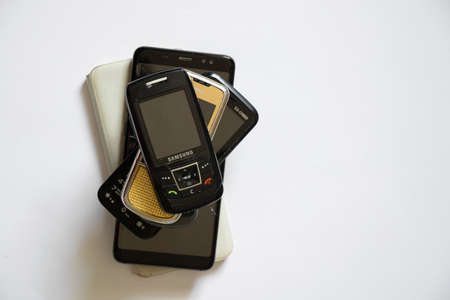 Ukraine Dnipro 08/10/2021 - phones of different models and different generations and brands lie on a white background, many different phonesのeditorial素材