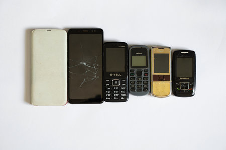 Ukraine Dnipro 08/10/2021 - phones of different models and different generations and brands lie on a white background, many different phonesのeditorial素材
