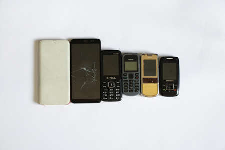 Ukraine Dnipro 08/10/2021 - phones of different models and different generations and brands lie on a white background, many different phonesのeditorial素材