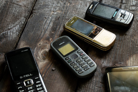 Ukraine Dnipro 08/10/2021 - phones of different models and different generations and brands lie on an old wooden board, many different phonesのeditorial素材