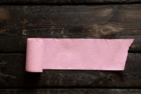 roll of pink toilet paper lies on an old wooden floor, toilet paperの写真素材