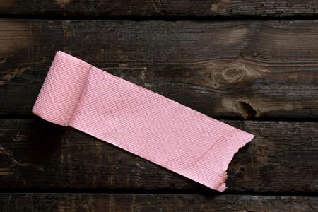 roll of pink toilet paper lies on an old wooden floor, toilet paperの写真素材