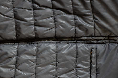 women's insulated black down jacket as a background with an open zipper, a background of soft black fabricの写真素材