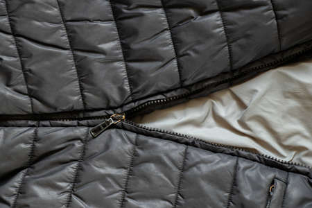women's insulated black down jacket as a background with an open zipper, a background of soft black fabricの写真素材
