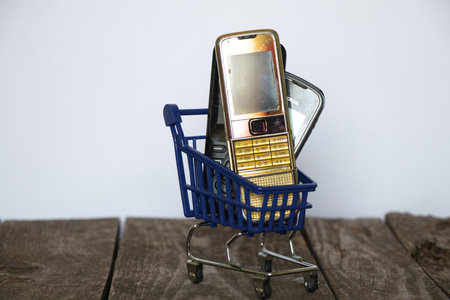 Ukraine Dnipro 08/10/2021 - phones of different models and different generations and brands are in a shopping cart for groceries on an old wooden board, many different phonesのeditorial素材