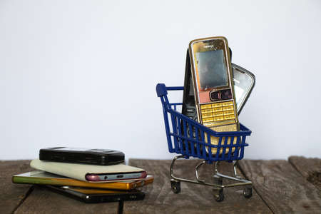 Ukraine Dnipro 08/10/2021 - phones of different models and different generations and brands are in a shopping cart for groceries on an old wooden board, many different phonesのeditorial素材