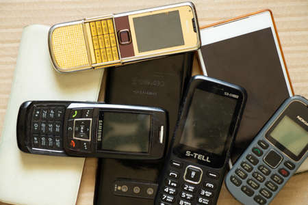 Ukraine Dnipro 08/10/2021 - phones of different models and different generations and brands lie on a brown paper background, many different phonesのeditorial素材