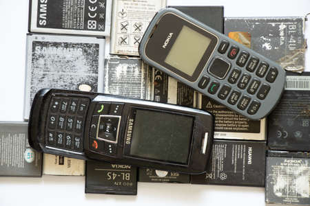 Ukraine Dnipro 08/10/2021 - on a white paper background there are phones of different models and different generations and brands next to batteries, many different phones and batteriesのeditorial素材