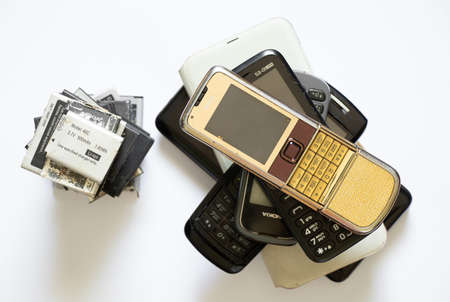 Ukraine Dnipro 08/10/2021 - on a white paper background there are phones of different models and different generations and brands next to batteries, many different phones and batteriesのeditorial素材