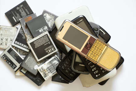 Ukraine Dnipro 08/10/2021 - on a white paper background there are phones of different models and different generations and brands next to batteries, many different phones and batteriesのeditorial素材