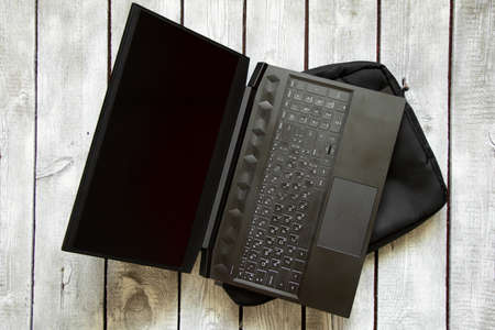 black laptop and black laptop bag lie on the written old wooden table, laptop on the tableの写真素材
