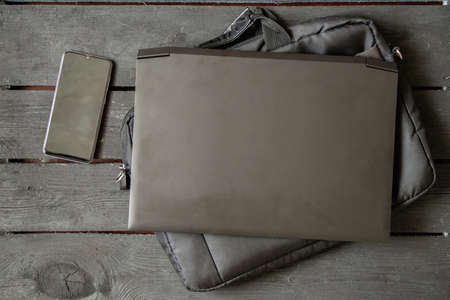black laptop and black laptop bag and phone lie on the written old wooden table, laptop on the table and phoneの写真素材