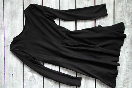 black long dress lies on a white wooden table, black fashion dressの写真素材