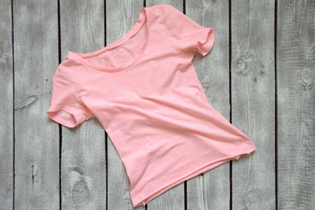 pink women's t-shirt lies on a white wooden table, t-shirt on a wooden backgroundの写真素材