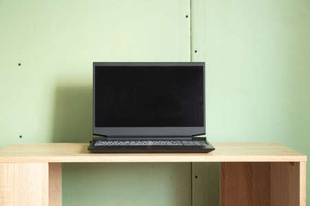 a black laptop with a black screen stands on a table in a room of a house with walls made of gypsum...