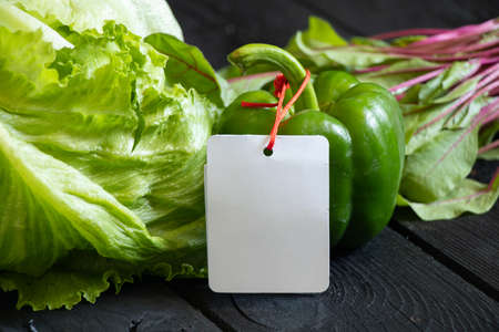 Swiss chard salad cabbage and pretz lies on a black wooden board with a clean blank white price tag, price of vegetables, salad, green vegetables on salad, healthy foodの写真素材