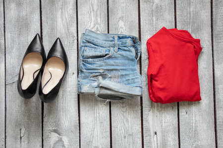 red jacket denim shorts and black leather shoes on a white wooden table, women's clothing on the tableの写真素材