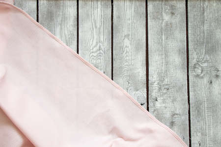 pink wrinkled tablecloth lies on a white wooden table as a background close-upの写真素材