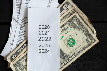 list of years 2020 2021 2022 2023 on the cash register that lies near the American dollars, sales receipt and money, financial topic, revenues in 2022の写真素材