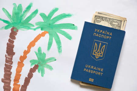 three palm trees painted with paint on white paper, a palm tree painted with paints, and next to it lie a foreign passport and dollars, a child's drawing, a palm tree for a seaside holidayの写真素材