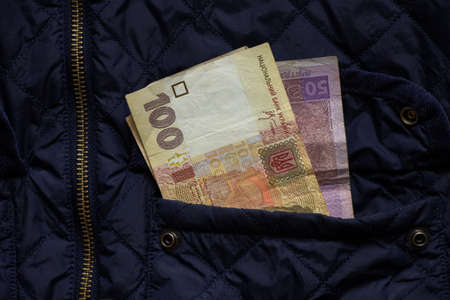 Ukrainian money one hundred and fifty hryvnia sticking out of the pocket of a blue jacket, Ukrainian money, financeの写真素材
