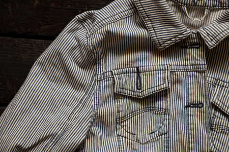 women's denim striped jacket lies on a wooden table, denim jacket striped black and white, fashionable clothesの写真素材