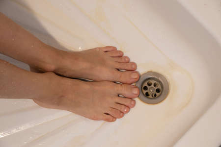 washing female feet in the bathroom, wet feet in the bathroom close-upの写真素材