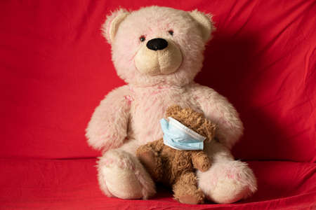 children's soft plush toys in medical mask lie on the red sofa, healthcare and medicine, children's morbidityの写真素材