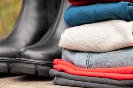 women's high black boots with thick soles and a pile of things stand on a wooden board in the sun on...