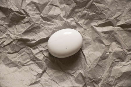 case with wireless headphones in the shape of an oval lies on crumpled gray paper, wireless headphones, musicの写真素材