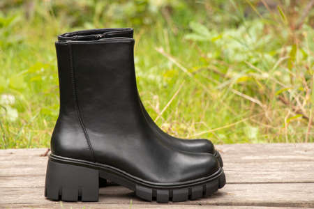 womens high black boots with thick soles stand on logs, womens shoes winter, footwear and fashionの写真素材