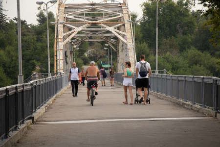 Ukraine Dnipro 08/31/2021 - people walk along the bridge in the park in the morning in August, people walk along the road, walkingのeditorial素材