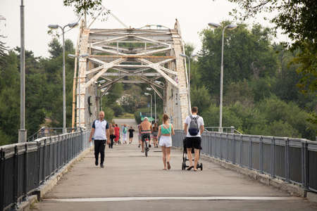 Ukraine Dnipro 08/31/2021 - people walk along the bridge in the park in the morning in August, people walk along the road, walkingのeditorial素材