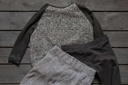 women's sweater and trousers lie on a black wooden table, women's fashion for warm clothesの写真素材