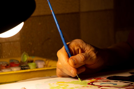 old woman paints a picture on canvas in oil in the dark by the light of a lamp, paint a picture at home, art and hobbies, grandma's hobbiesの写真素材