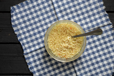 boiled pasta with yushka in a plate on a black wooden table for lunch, noodles in a plate on the tableの写真素材