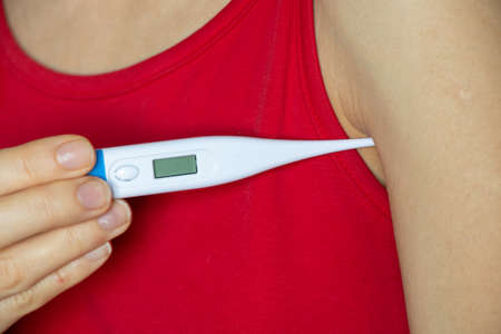 young girl with a thermometer in her hand, high temperature, fever and fever, worldwide pandemic,...