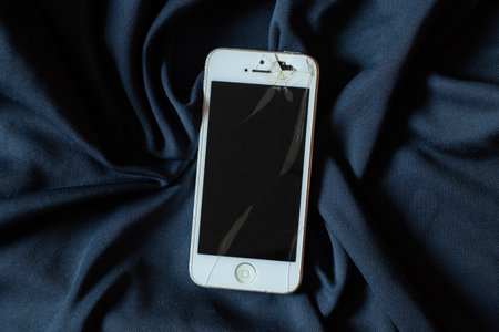 Ukraine Dnipro 11/18/2021 - iPhone 4 lies on an isolated background, broken screen on the phone, broken phoneのeditorial素材