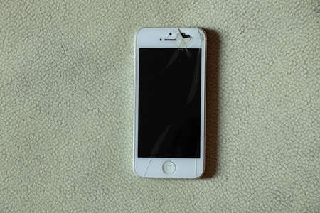 Ukraine Dnipro 11/18/2021 - iPhone 4 lies on an isolated background, broken screen on the phone, broken phoneのeditorial素材
