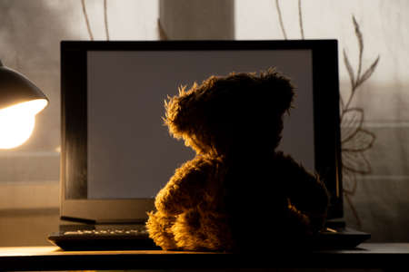 teddy bear for children sits carrying a laptop on the table, carrying a table lamp in the bedrooms at night, carrying windows, loneliness, joy in a laptopの写真素材