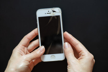 Ukraine Dnipro 11/18/2021 - iPhone 4 broken female hands hold on an isolated background, broken...