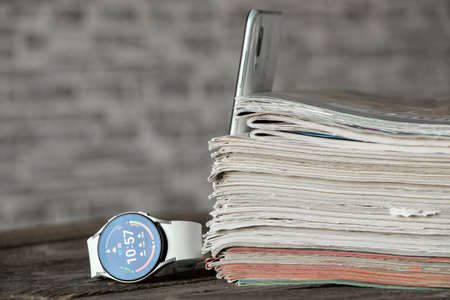 Ukraine Dnipro 11/30/2021 Smart watch Samsung Galaxy Watch 4 and a stack of old magazines on the table, a clock and a stack of magazines, newsのeditorial素材