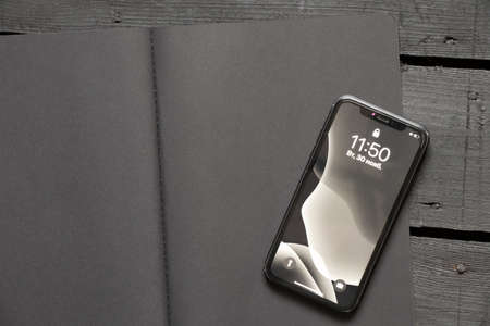 Ukraine Dnipro 11/30/2021 - The Apple iPhone 11 smartphone lies on a black notebook on a black...