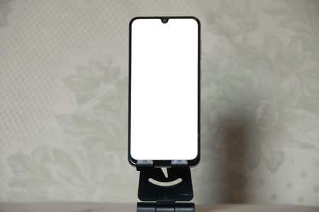 phone with a white screen on a stand on a table at home, a phone with a white screenの写真素材