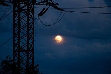 power line against the background of the moon in the sky at sunset at night in Ukraine, the night sky and the moon the city of Dniproの写真素材